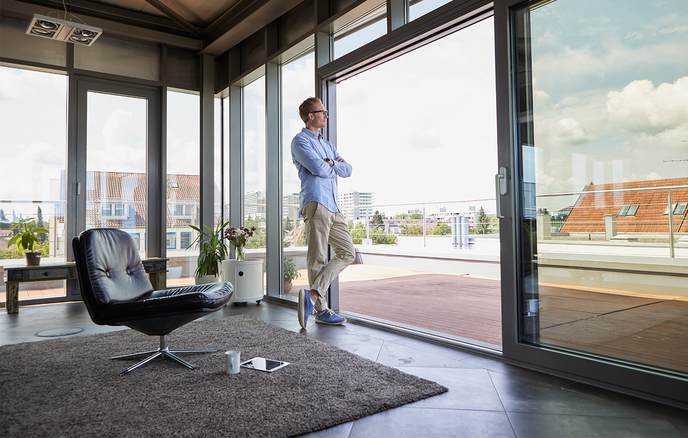 Mann steht in einem Büro vor einer großen Fensterfront mit Blick auf die Stadt.